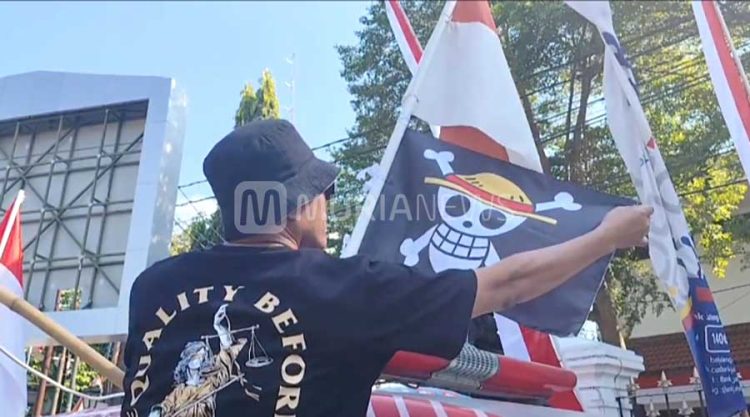 Masyarakat Pati Bersatu mengibarkan bendera One Piece alias Jolly Roger di bawah bendera merah putih di sebelah barat laut Alun-alun Pati, Minggu (3/8/2025) (foto: MuriaNews)